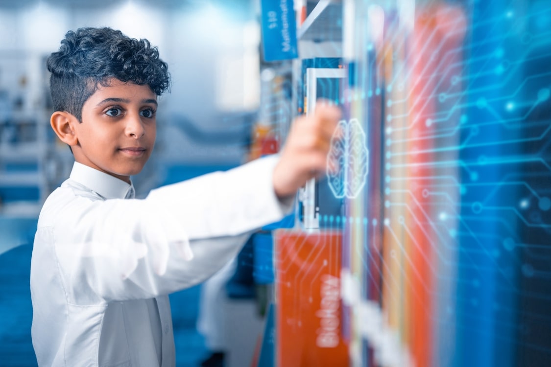 A young boy in a lab coat is engaged with a big screen, exploring and interacting with its contents