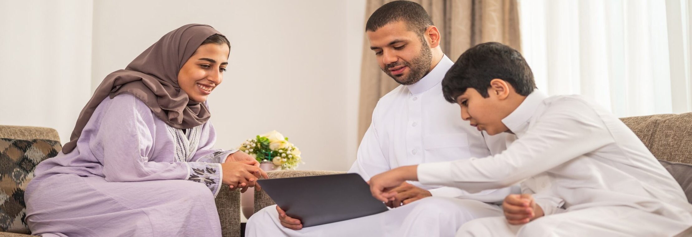 An Arab family sitting on a couch with a laptop, showcasing tech and innovation in their home