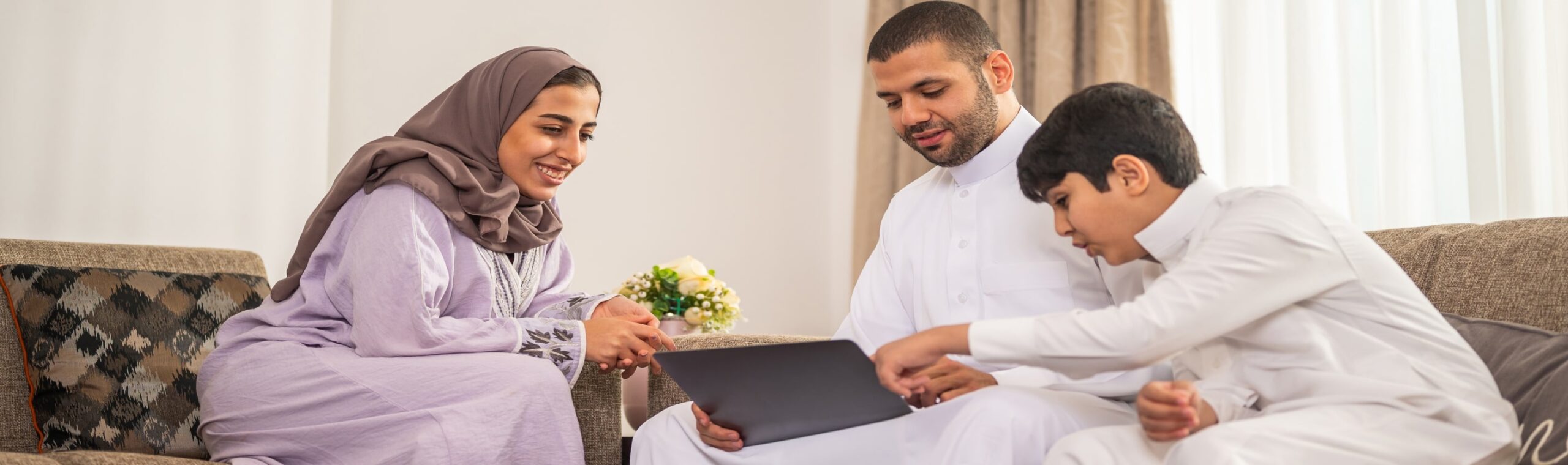 An Arab family sitting on a couch with a laptop, showcasing tech and innovation in their home