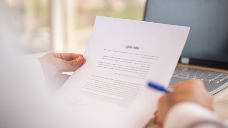 A person holding a pen, looking at a document