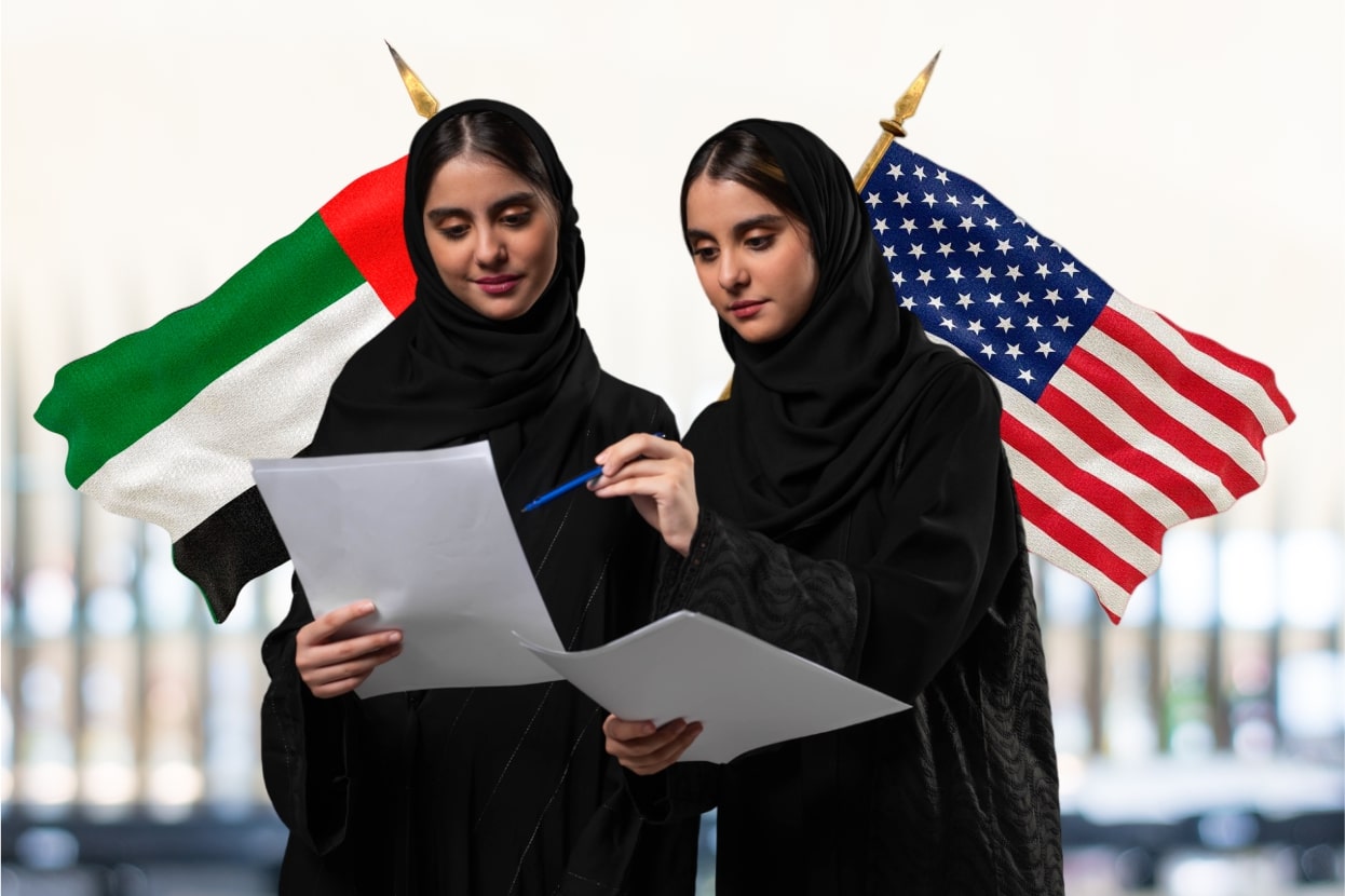Two Arab women in black Abayas holding papers, discussing Innovation and US & UAE flags in background